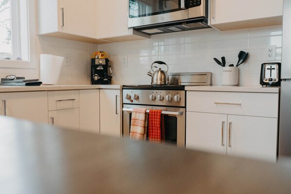 Una cocina moderna con estufa, horno, microondas y cafetera.