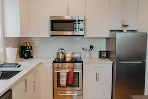Eine moderne Küche mit Edelstahlgeräten, darunter eine Mikrowelle, ein Backofen und ein Kühlschrank.