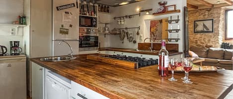 A kitchen with a wooden countertop, a sink, and various appliances including a refrigerator and ovens.