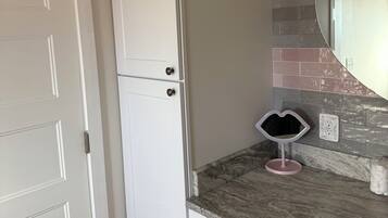 Een badkamer met een wit wastafelmeubel, een spiegel en een betegelde spatwand.