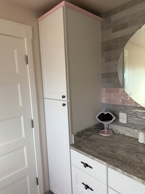 Une salle de bain avec un meuble-lavabo blanc, un miroir et un pare-feu en carreaux.