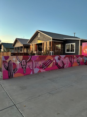 A building with a covered porch and a mural on the adjacent wall.