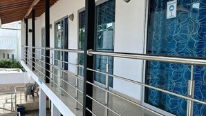 A covered outdoor area with a metal railing, a covered walkway, and a building with patterned glass doors. - Hotel Caribe Covenas (Tolú)