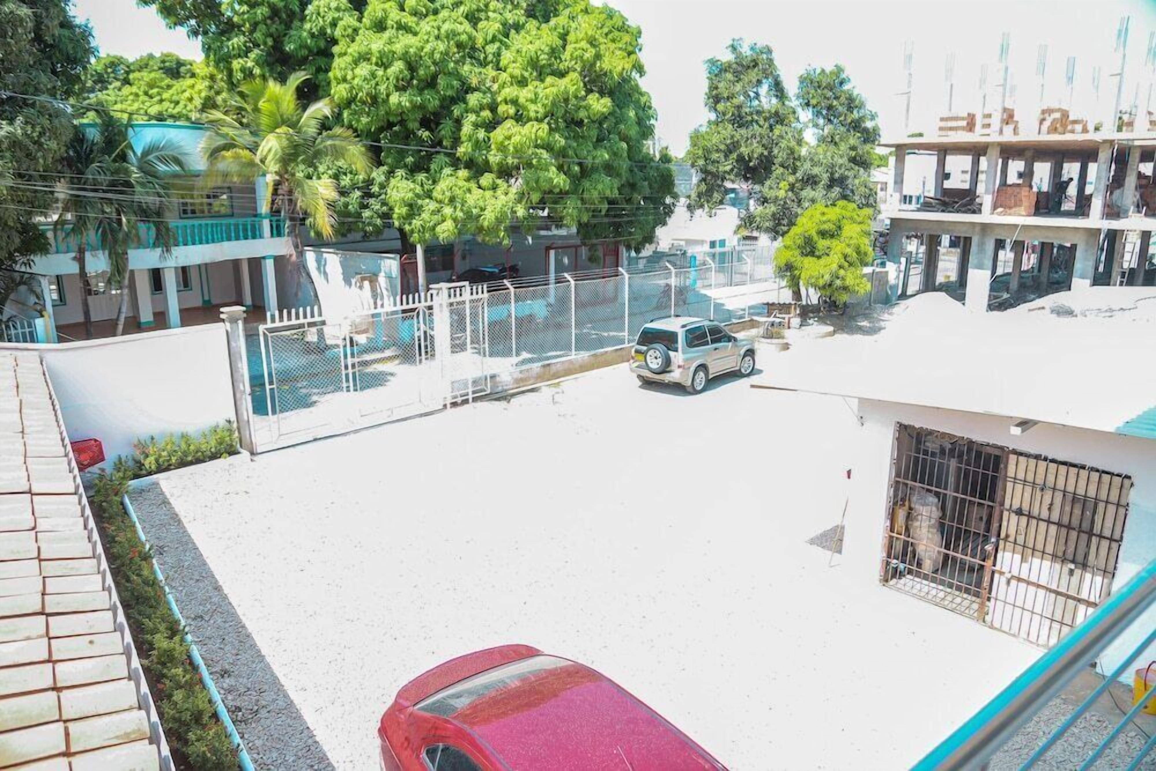 Uma área de estacionamento com um carro vermelho, um carro branco e um edifício em construção.