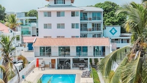 A hotel with a swimming pool, multiple balconies, and palm trees. - Hotel Caribe Covenas (Tolú)
