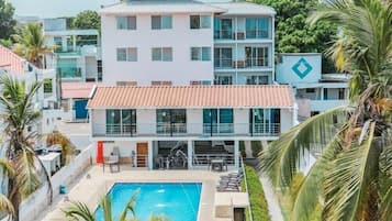 Un hotel con piscina, varios balcones y palmeras.