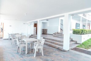 Amplio espacio al aire libre con comedor, escalones de piedra y vista a un edificio de fondo.