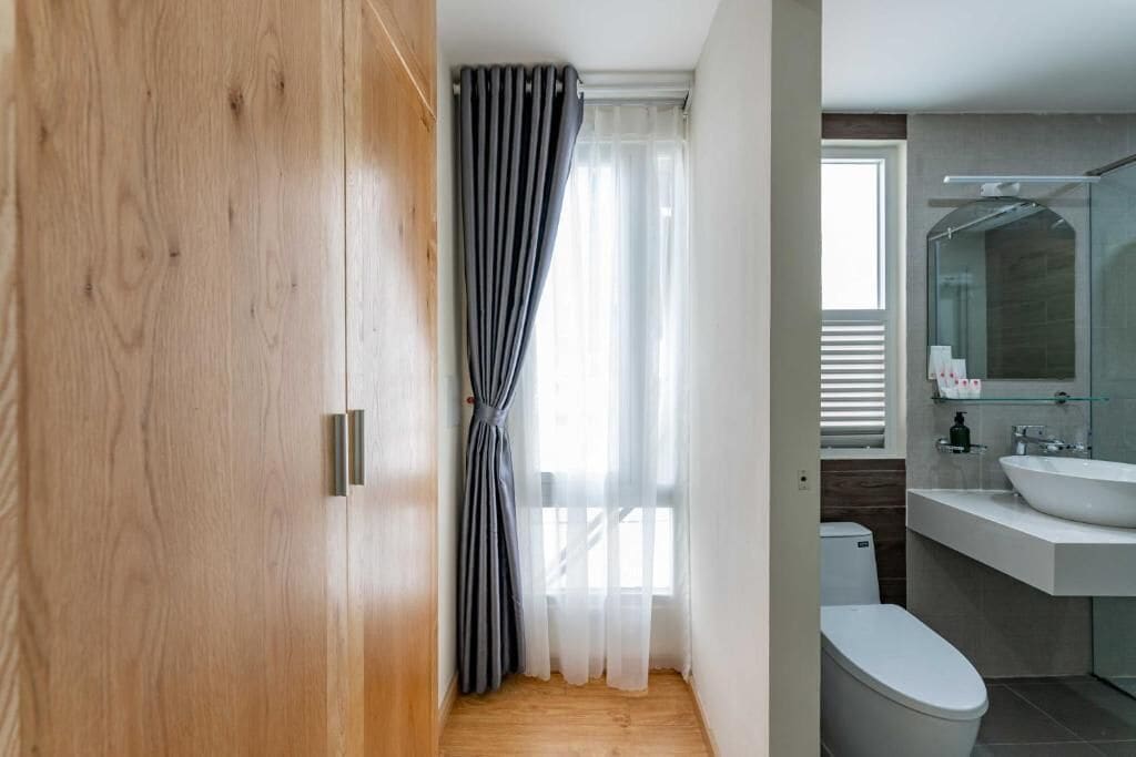 A modern bathroom with a wooden floor, a white toilet, a glass shower enclosure, and a white sink.