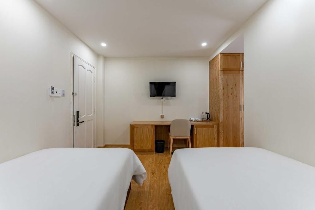 A hotel room with two beds, a desk, a television, and a wardrobe.