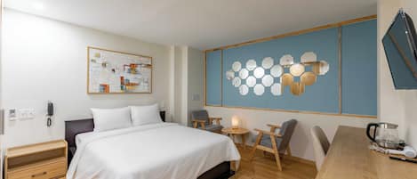 Une chambre d’hôtel comprenant un lit, une table de chevet, une chaise, un bureau et un téléviseur fixé au mur.