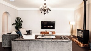 A modern living room with a grey sofa, a flat-screen TV, a wooden coffee table, and a fireplace. - Welcome to the House of Ferment. Walk to everything in Orange (Orange)