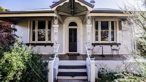 A two-story house with a front porch, a central entrance, and a small garden area. - Welcome to the House of Ferment. Walk to everything in Orange (Orange)