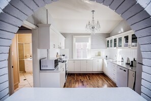 Eine moderne Küche mit weißen Schränken, Holzboden und einer Pendelleuchte.