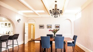 A dining area with a wooden table, blue upholstered chairs, a chandelier, and framed pictures on the wall. - Welcome to the House of Ferment. Walk to everything in Orange (Orange)