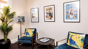 A room with two blue armchairs, a small round table, and a potted plant. There are three framed posters on the wall. - Welcome to the House of Ferment. Walk to everything in Orange (Orange)