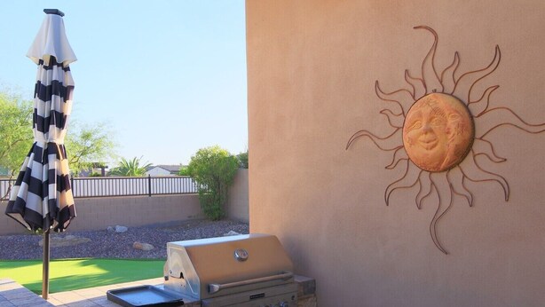 En grill, en parasol og en sol dekoration ophængt på en væg.