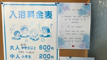 A bulletin board with a sign listing bath fees for different categories of people and a notice about bathroom amenities.