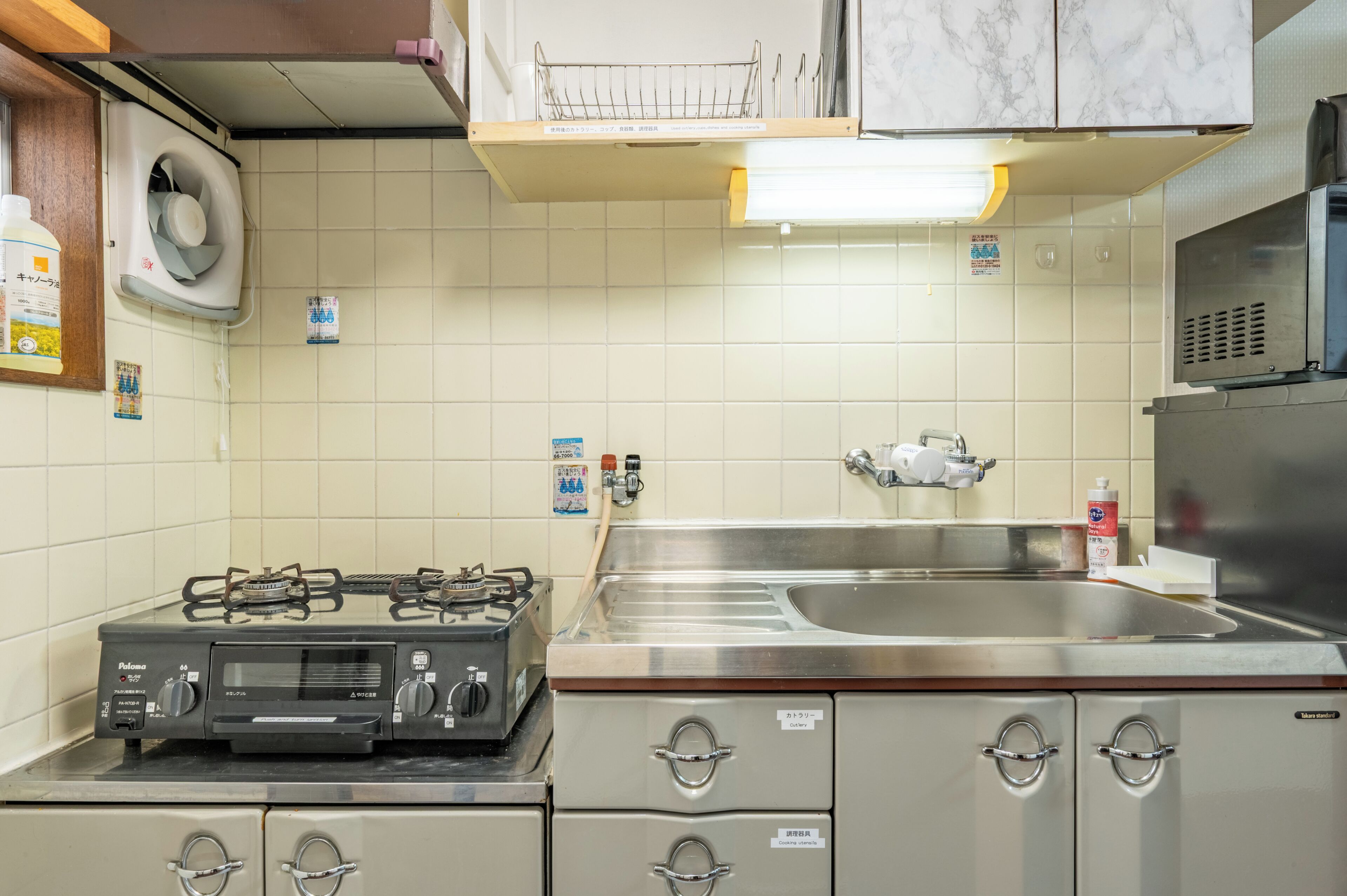 A kitchen with a gas stove, stainless steel sink, and cabinets.
