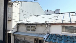 Un edificio residencial con techo de lámina corrugada, cableado eléctrico visible y entrada con portón.