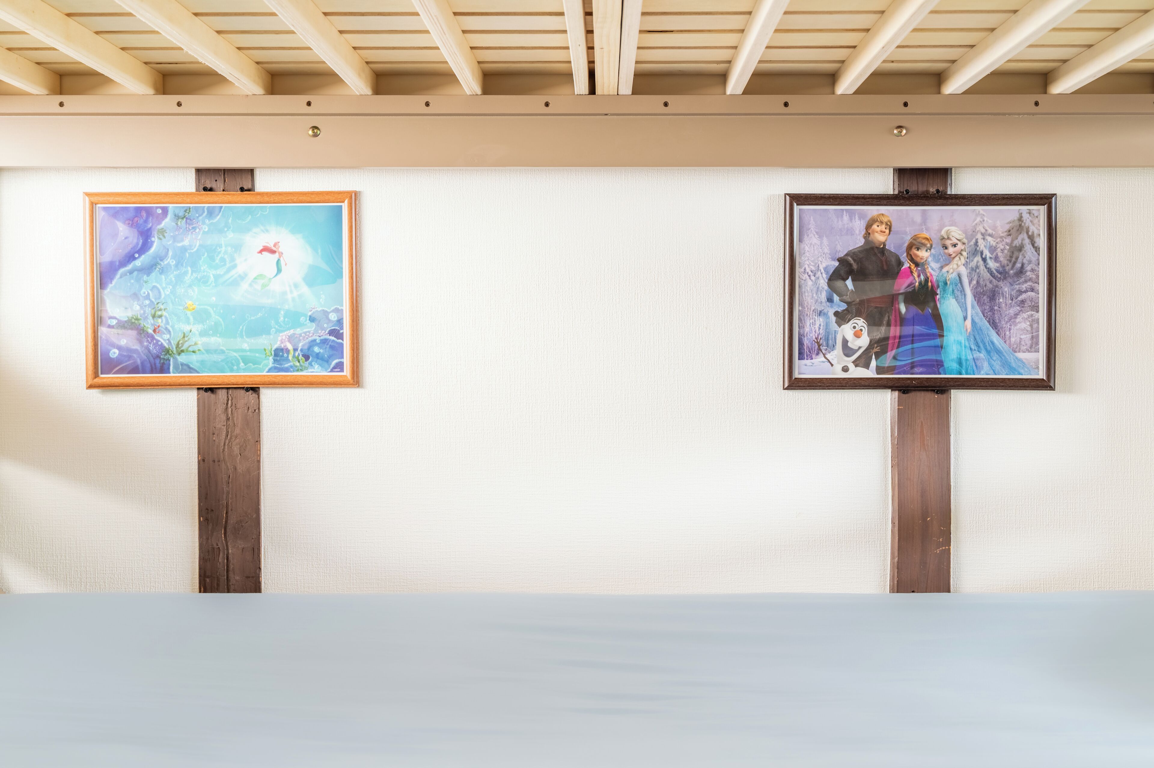 Two framed artworks on wooden stands against a plain wall.