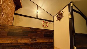 A hotel lobby with a wooden wall displaying street names, a life preserver hanging on the wall, and a ship's wheel decoration. - Atlantis Tengachaya (Nishinari-ku, Osaka City)