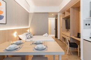 Ein modernes Hotelzimmer mit Essbereich, einem Bett und einem Fernseher.
