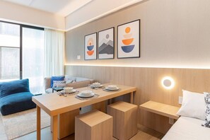 A modern hotel room with a dining area, a sofa, and artwork on the wall.