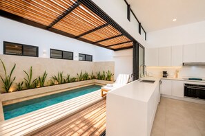 Eine moderne Küche mit integrierter Kochinsel, einem Pool und einer Sitzecke mit Blick auf den Pool.