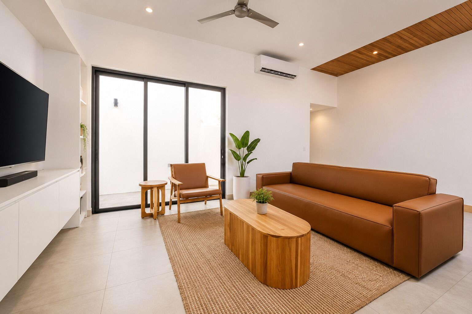 A modern living room with a flat-screen TV, a brown leather sofa, a wooden coffee table, and a small side table.