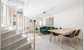 A modern interior with a staircase, a dining area, and a green sofa. - AT A SHORT DISTANCE FROM THE CITY CENTER & THE BEAUTIFUL MEDITERRANEAN BEACHES (Cannes)
