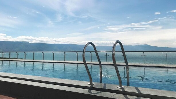 Piscina con barandales de metal y vistas a montañas al fondo.
