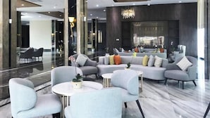 Un vestíbulo moderno con un sofá seccional, sillones y una mesa redonda.