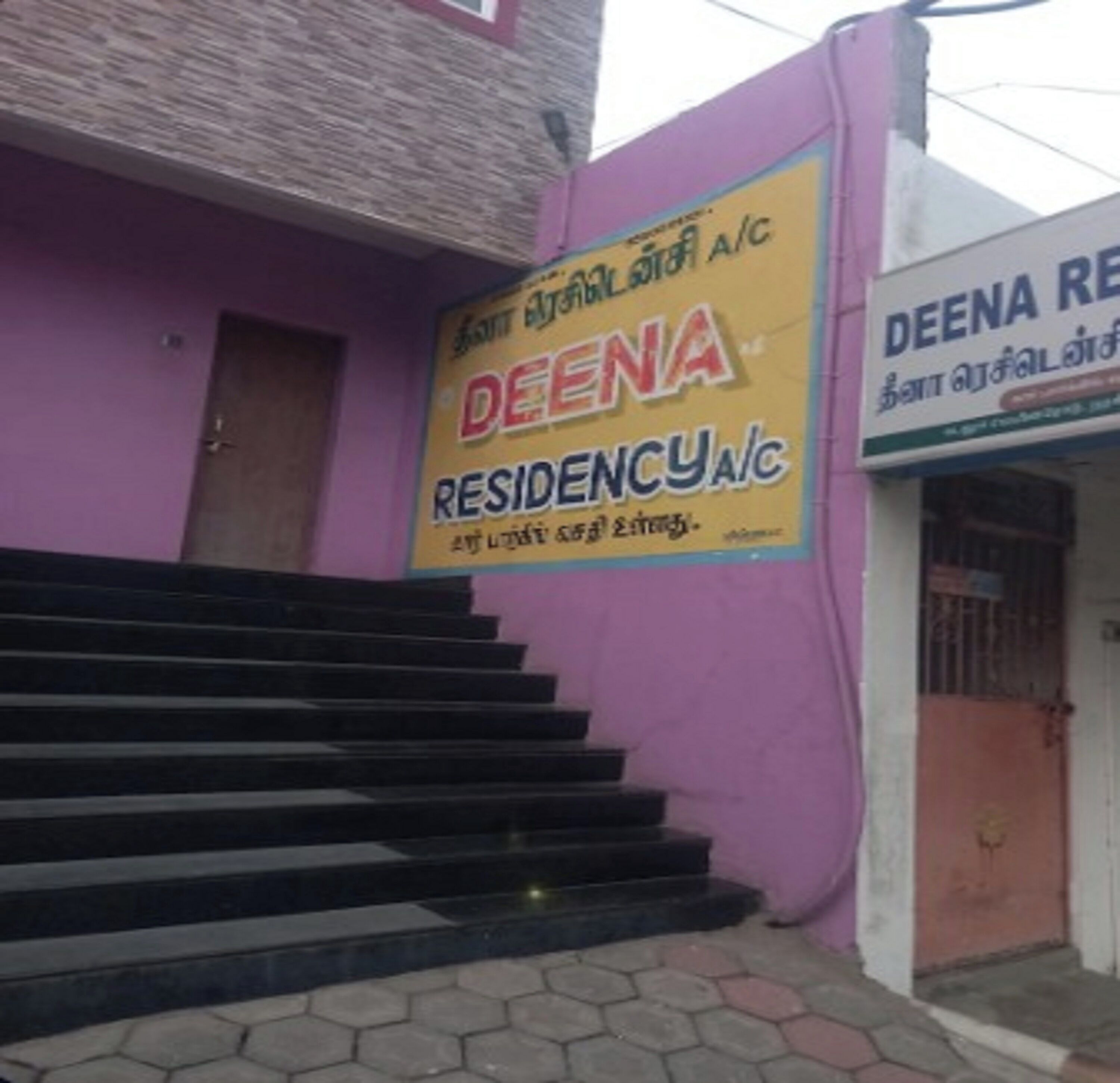 En bygning med et skilt for 'DEENA RESIDENCY A/C' og en trappe, der fører op til indgangen.