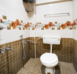A bathroom with a toilet, shower, and tiled walls. - Deena Residency (Attur)
