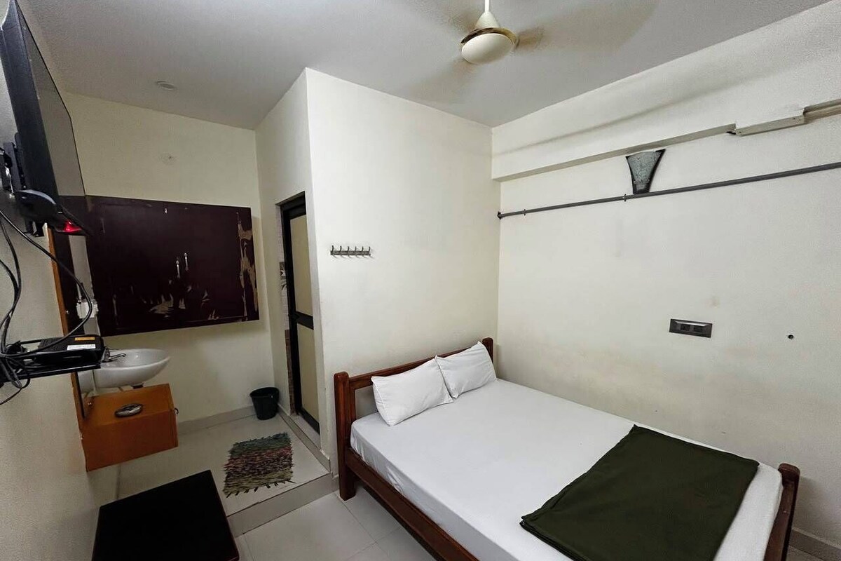 Un dormitorio con una cama individual, una mesita de noche, un espejo, un mueble pequeño y un ventilador de techo.