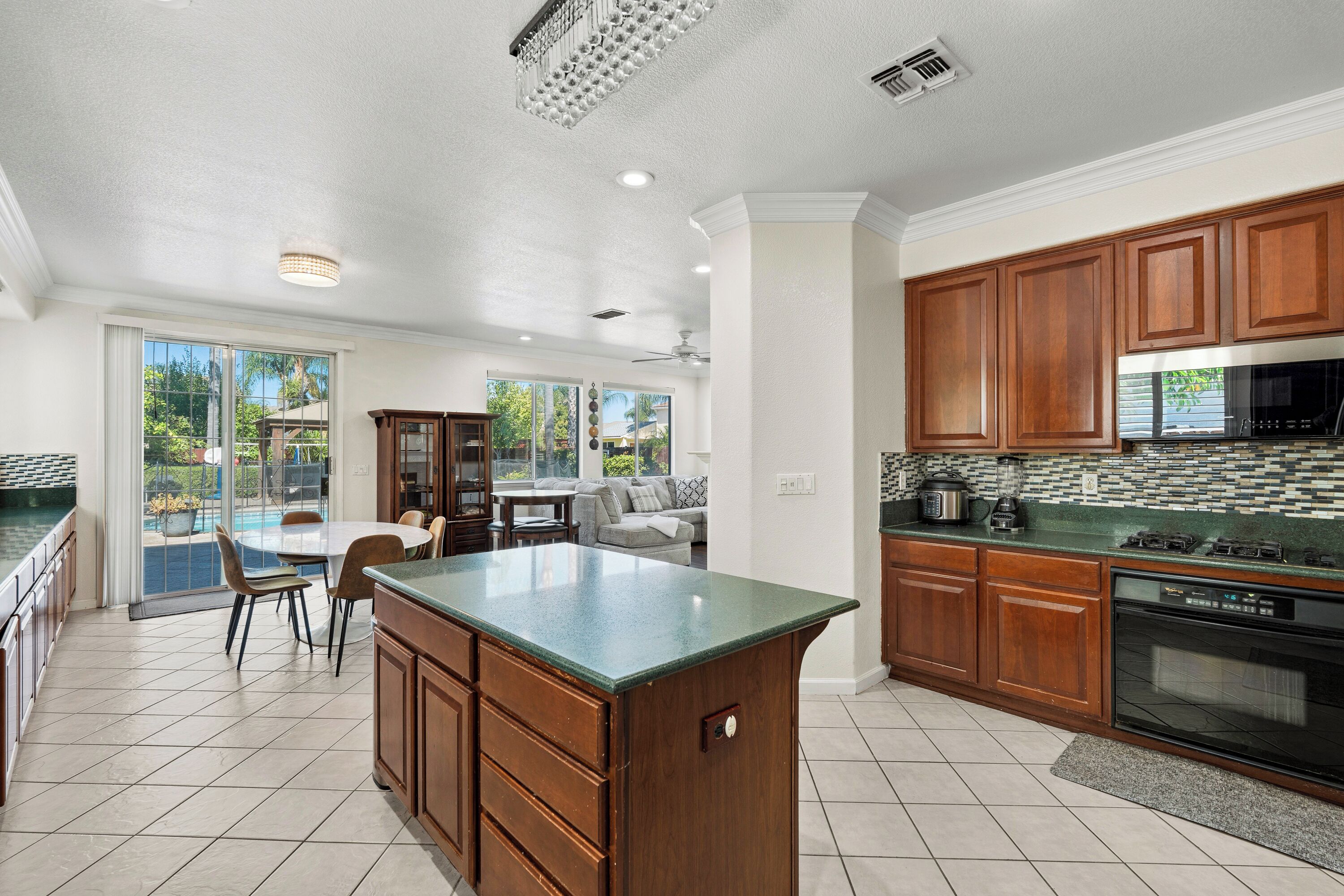 A spacious kitchen with a large island, wooden cabinets, and a view to the outside.