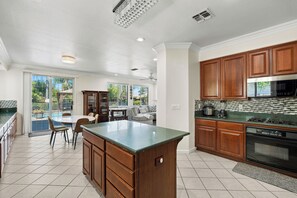 Uma cozinha espaçosa com uma grande ilha, armários de madeira e vista para o exterior.