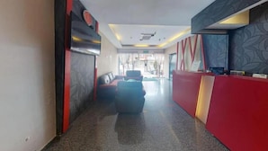 Un hall de hotel con mostrador de recepción, zona de estar y una vista despejada de la entrada.