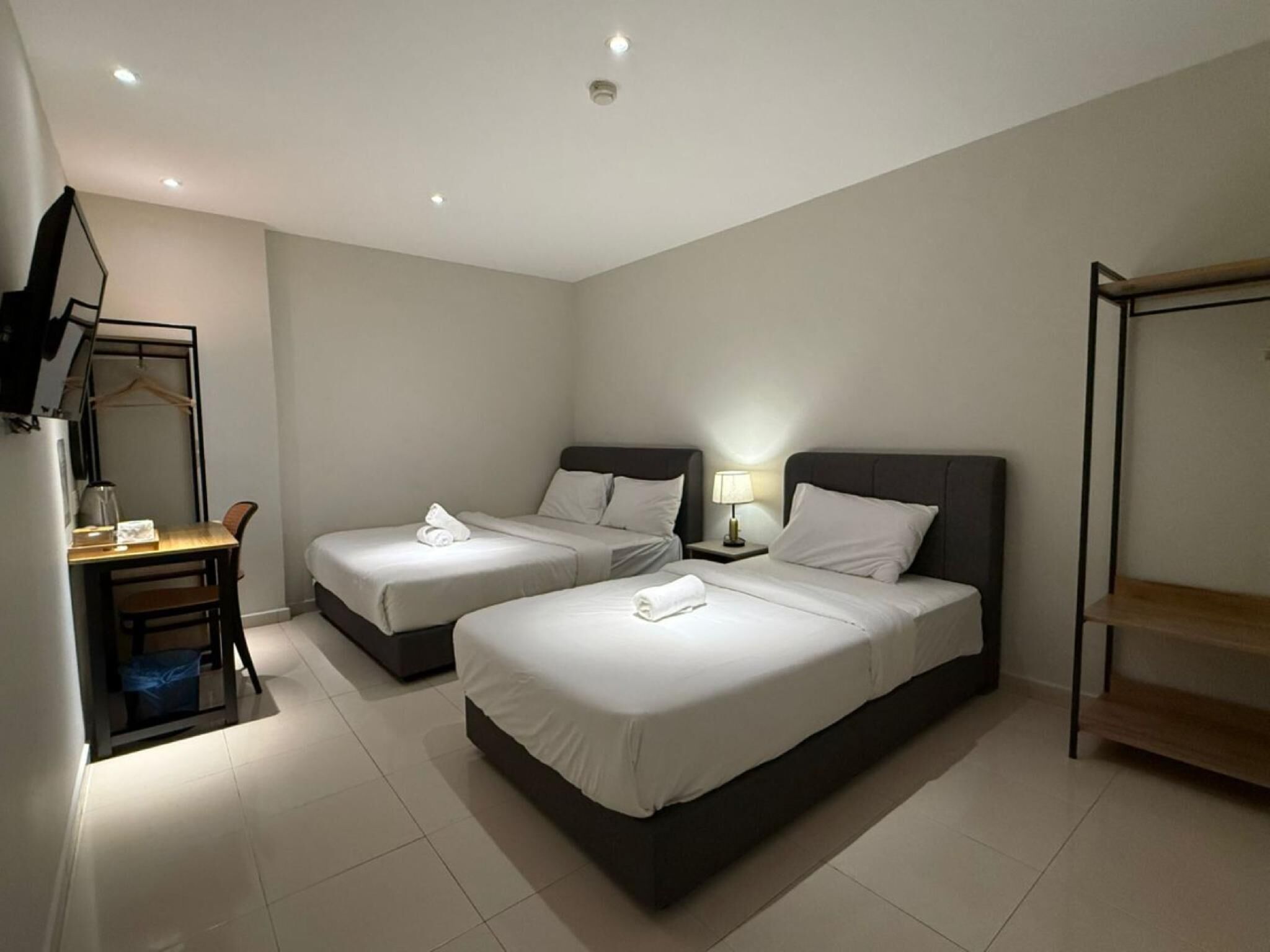 A hotel room with two beds, a desk, a chair, a TV, and a wardrobe.