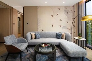Una sala moderna con un sofá modular, un sillón individual, una mesa de centro redonda y una lámpara de pie.