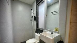 Et lille, moderne badeværelse med toilet, håndvask og bruser.