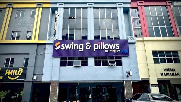 En bygning med et skilt, der viser 'Swing & Pillows', og et andet skilt, der viser 'Wisma Mariamah'.