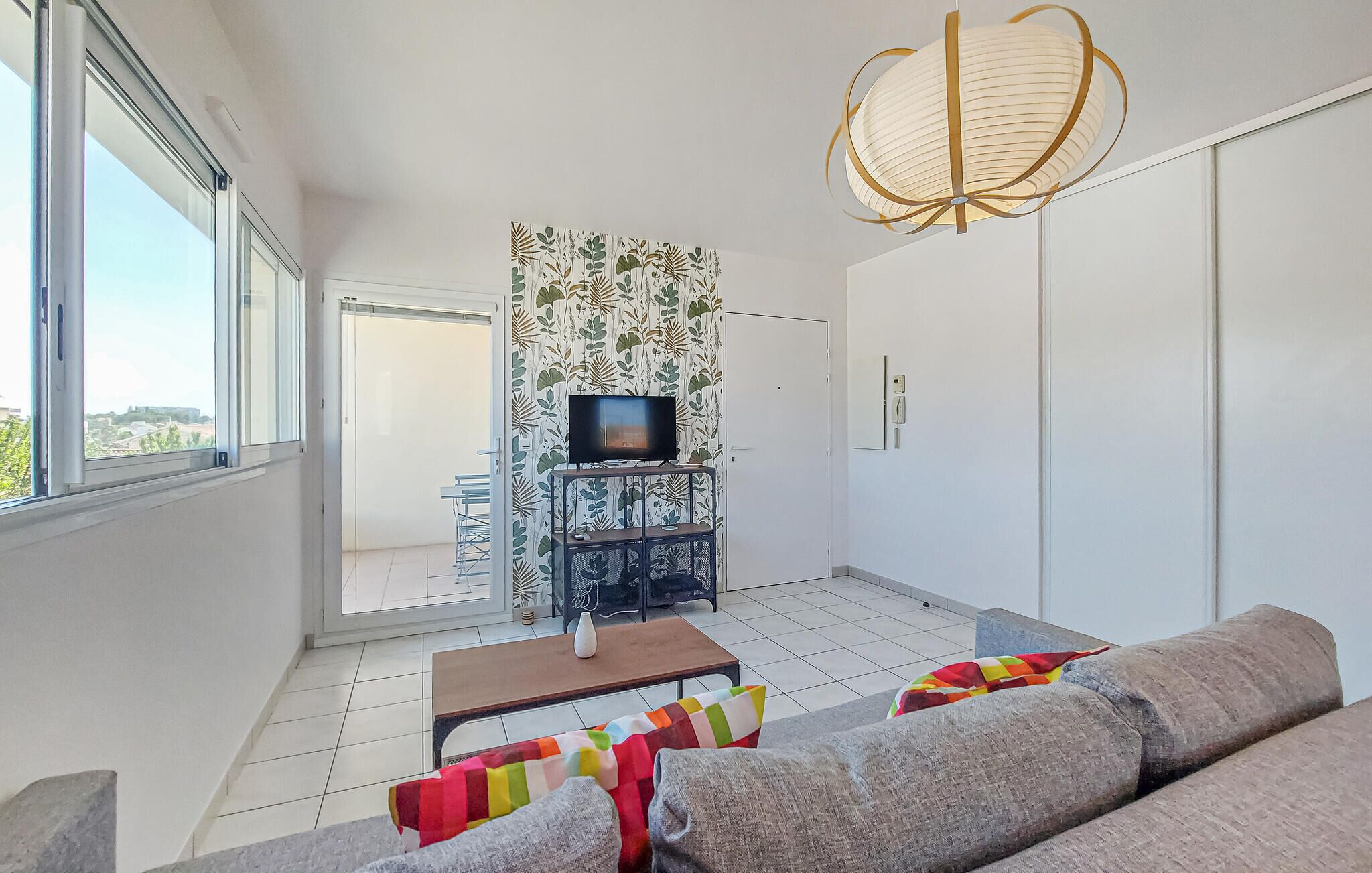 A modern living room with a sofa, a coffee table, a TV on a stand, and a patterned wallpaper.