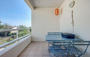 A balcony with a table and chairs, a suitcase, a wall clock, and a hanging plant. - Charmant appart. proche plage (Royan)