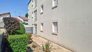 A residential building with a paved pathway, a small garden, and a fence. - Charmant appart. proche plage (Royan)