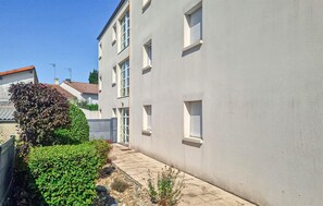 Ein Wohngebäude mit gepflastertem Weg, einem kleinen Garten und einem Zaun.