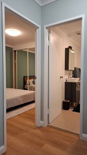 Ein Schlafzimmer mit Bett und ein Badezimmer mit Waschbecken und Spiegel.