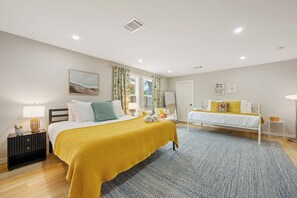 Ein Hotelzimmer mit zwei Betten, einem großen Fenster mit Vorhängen, einem Nachttisch mit Lampe sowie einer Stehlampe.