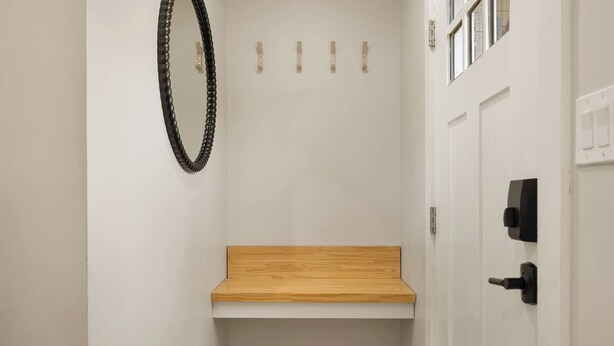 A bathroom with a wooden bench, a white door with a black handle, and a mirror with a black frame. - Pickleball, Pool, Games, Mins to Zilker, SoCo/DT (Austin)