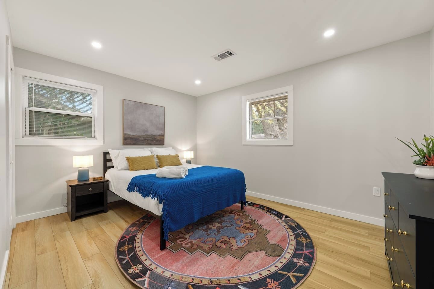 A bedroom with a bed, bedside tables, a rug, and a window.